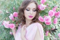 Beautiful girl in a pink dress standing in the garden roses in a sunny bright summer day with a gentle make-up and bright puf Royalty Free Stock Photo