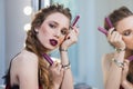 Beautiful girl with professional makeup at the mirror, advertises cosmetics, lipstick Royalty Free Stock Photo