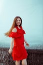 Beautiful sexy girl in a red dress with long hair laughs. Woman dancing near a fountain in the rain with wet hair Royalty Free Stock Photo