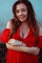 Beautiful sexy girl in a red dress with long hair laughs. Woman dancing near a fountain in the rain with wet hair Royalty Free Stock Photo