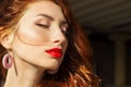 Beautiful girl with red hair with big red lips with makeup in the city on a Sunny summer day Royalty Free Stock Photo