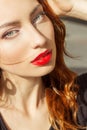 Beautiful girl with red hair with big red lips with makeup in the city on a Sunny summer day Royalty Free Stock Photo