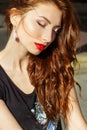 Beautiful girl with red hair with big red lips with makeup in the city on a Sunny summer day Royalty Free Stock Photo