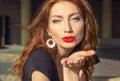 Beautiful girl with red hair with big red lips with makeup in the city on a Sunny summer day Royalty Free Stock Photo