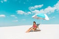 Beautiful sexy girl in swimsuit and sunglasses sitting in deck chair under umbrella on sandy beach Royalty Free Stock Photo