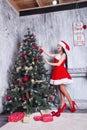 Beautiful girl wearing santa claus clothes . Young woman decorating Christmas tree with red balls at home Royalty Free Stock Photo