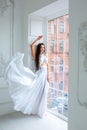 Beautiful girl in white dress by the window. romantic image. fashion indoor portrait of elegant woman in luxurious dres