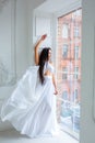 Beautiful girl in white dress by the window. romantic image. fashion indoor portrait of elegant woman in luxurious dres
