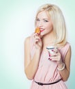 Beautiful gorgeous blonde girl with bright makeup in pink dress in the Studio on a white background sitting