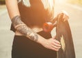 A beautiful, hipster blonde with blue hair in tattoo stands with a longboard Royalty Free Stock Photo