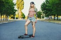 beautiful, hipster blonde with blue hair in tattoo stands with a longboard Royalty Free Stock Photo