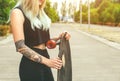 A beautiful, sexy hipster blonde woman with blue hair in tattoo stands with a longboard  on the street.Longboard riding and sport Royalty Free Stock Photo