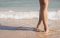 Beautiful sexy legs on the beach. Women`s legs on a sandy beach against the background of a wave Royalty Free Stock Photo