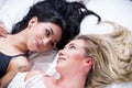 Beautiful lesbians lovers at morning laying in bed, doing a heart form with their hair, in a white background