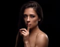 Beautiful sexy long hair girl showing secret sign holding the finger near the lips and looking passion. Closeup portrait isolated