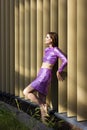 slim woman in purple (violet) glitter (sequins)crop top and skirt,leans against wooden beams of building