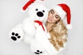 Beautiful sexy, smiling blonde model dressed in a Santa Claus hat, holding a teddy bear. Beauty sensual girl for Christmas Royalty Free Stock Photo