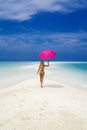 Beautiful sexy tanned woman bikini model with pink umbrella on Maldives island. Young glamour girl in swimsuit on Maldives Royalty Free Stock Photo