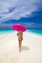 Beautiful sexy tanned woman bikini model with pink umbrella on Maldives island. Young glamour girl in swimsuit on Maldives Royalty Free Stock Photo