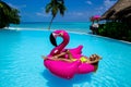 Beautiful sexy tanned woman on pink flamingo in pool. Young glamour girl in swimsuit on Maldives island. Perfect body bikini model Royalty Free Stock Photo