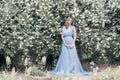 Beautiful tender blonde girl in blue light dress with a sprig of jasmine in his hands sitting the garden in the style Royalty Free Stock Photo