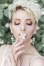 Beautiful tender girl with short haircut in cream dress with jasmine flower