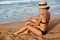 Beautiful Sexy Woman in bikini apply sun protection cream on her smooth tanned legs. Skin care. Legs on the beach Royalty Free Stock Photo
