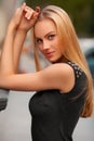 Beautiful woman with black dress and blond hair posing outdoor. Fashion girl portrait Royalty Free Stock Photo