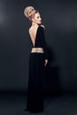 Beautiful sexy woman in black evening dress with open back on a black background. Royalty Free Stock Photo