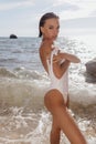 Beautiful sexy woman with dark hair in elegant swimming suit posing on the summer sunset beach Royalty Free Stock Photo