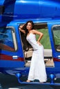 Beautiful sexy woman with dark hair in luxurious dress posing near blue helicopter
