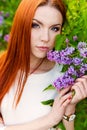 Beautiful woman with fiery regime hair with eyes of a Fox in the garden with lilacs