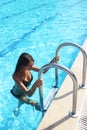 Beautiful woman with perfect slim figure with long wet hair and bathing suit coming out of swimming pool on stairs swim, sunb Royalty Free Stock Photo