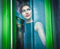 Beautiful woman posing in a green painted window frame, shot through window. gorgeous young female with long curly hair