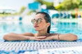 Young pretty woman in sunglasses looking at camera while swimming in pool Royalty Free Stock Photo