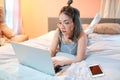 Beautiful and sexy woman using laptop computer and listening to music from cell phone on bed Royalty Free Stock Photo