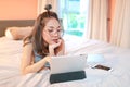 Beautiful and sexy woman using laptop computer and listening to music from tablet on bed Royalty Free Stock Photo