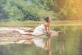 Beautiful sexy women in white light dress sitting on the rock. Sexy model sitting along the lake quiet and peace place for Royalty Free Stock Photo