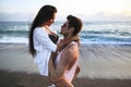 Beautiful, sexy, young caucasian couple cuddling on the beach at sunset time near ocean during summer vacation o