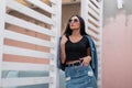 Beautiful sexy young hipster woman in a stylish denim jacket in a trendy black top in a vintage jeans skirt in sunglasses Royalty Free Stock Photo