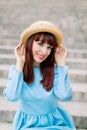 Beautiful sexy young red haired woman wearing blue dress and hat, posing to camera while sitting on city stairs outdoors Royalty Free Stock Photo