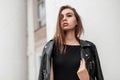 Beautiful sexy young woman with brown hair in fashionable black clothes posing in the city near a vintage building. Attractive Royalty Free Stock Photo