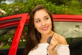 Beautiful young woman holding her keys and smiling and a red car behind Royalty Free Stock Photo