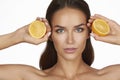 Beautiful young woman with perfect healthy skin and long brown hair day makeup bare shoulders holding orange lemon grapefruit Royalty Free Stock Photo