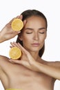 Beautiful young woman with perfect healthy skin and long brown hair day makeup bare shoulders holding orange lemon grapefruit Royalty Free Stock Photo