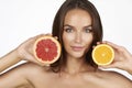 Beautiful young woman with perfect healthy skin and long brown hair day makeup bare shoulders holding orange lemon grapefruit Royalty Free Stock Photo