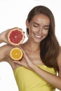 Beautiful young woman with perfect healthy skin and long brown hair day makeup bare shoulders holding orange lemon grapefruit Royalty Free Stock Photo