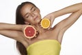 Beautiful young woman with perfect healthy skin and long brown hair day makeup bare shoulders holding orange lemon grapefruit Royalty Free Stock Photo