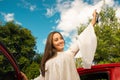 Beautiful young woman wearing a white blouse coming out of her red car and holding a keys while she is smiling Royalty Free Stock Photo