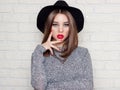 Beautiful young girl in a black hat with red full lips, bright makeup and painted my nails red Royalty Free Stock Photo